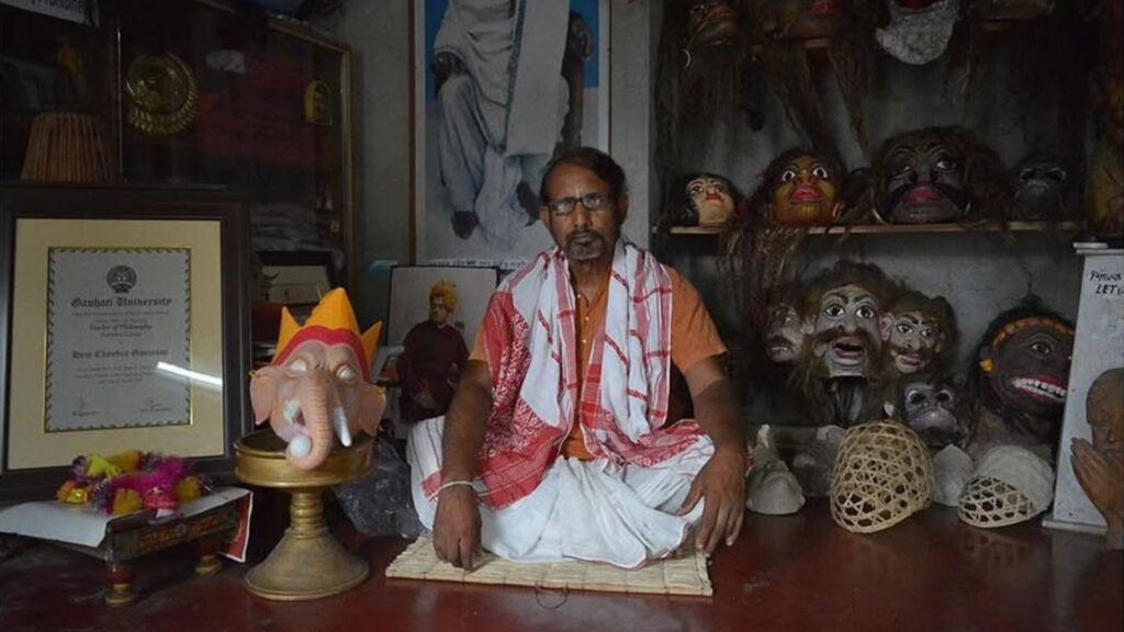 Hem Chandra Assamese mask artist seated with traditional masks around him.