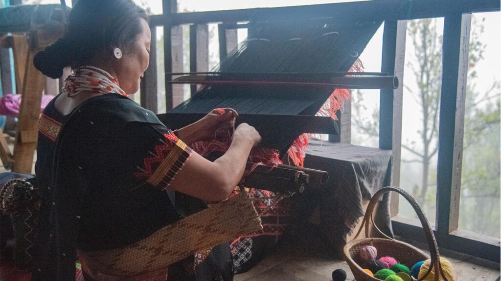 Idu Mishmi woman weaving on a traditional loom with colourful threads.