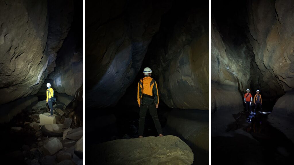 Cavers standing inside narrow cave chamber