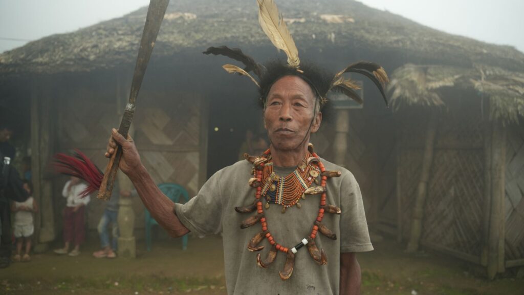 Elderly man in traditional attire with feathers