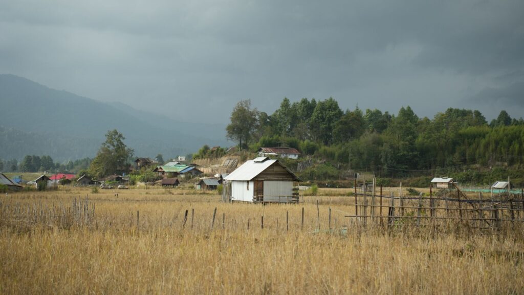 Village huts beside mountains and fields.