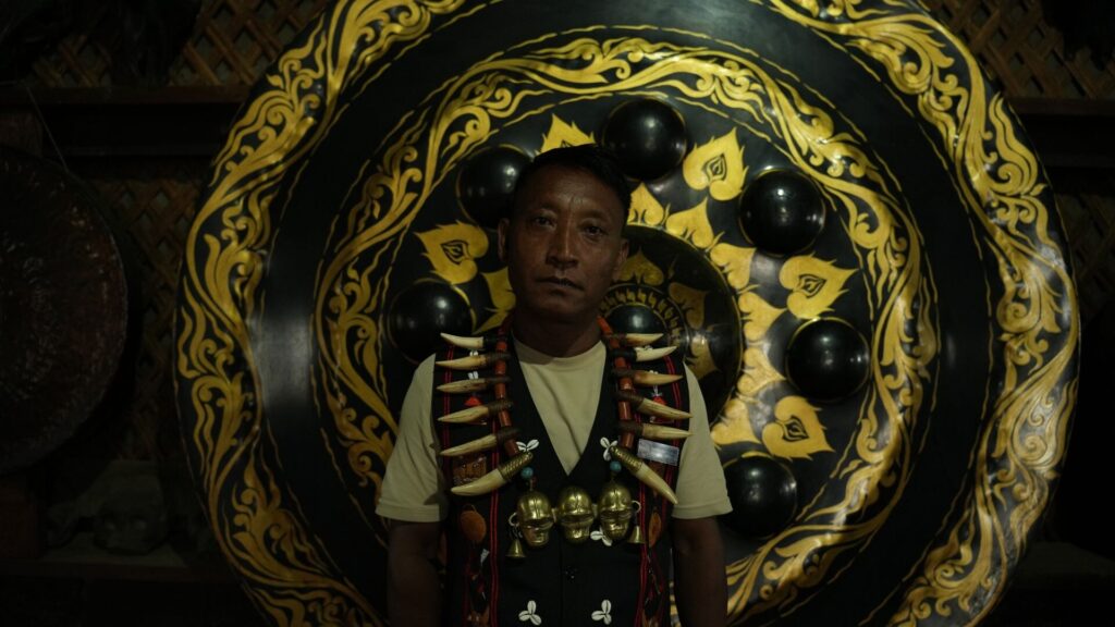 Konyak elder wearing warrior necklace inside decorated morung.