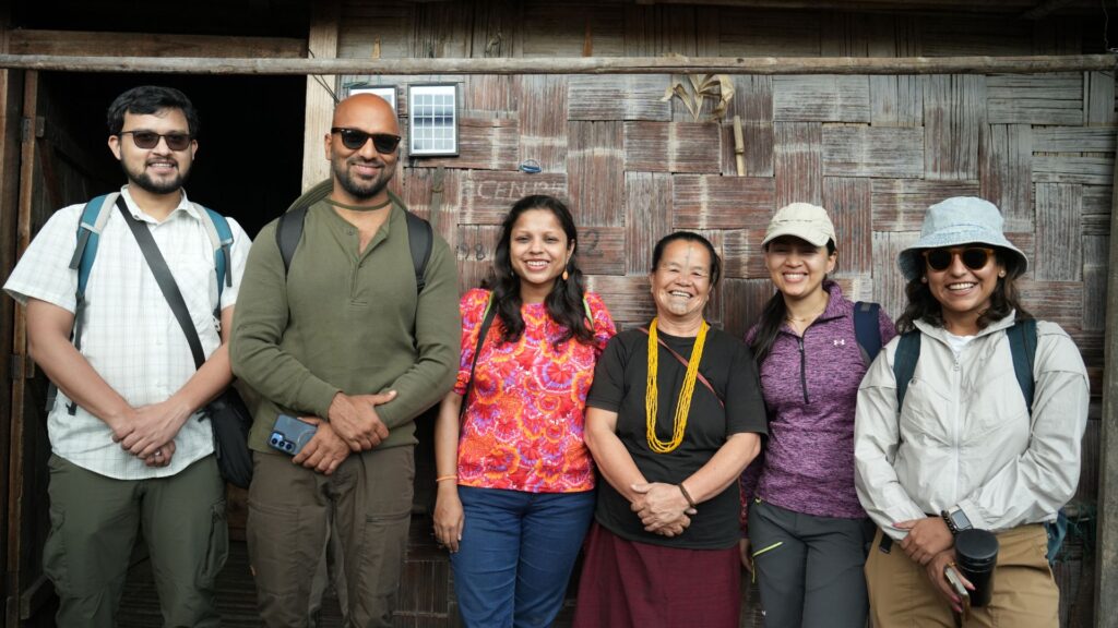 Visitors smiling outside traditional bamboo house