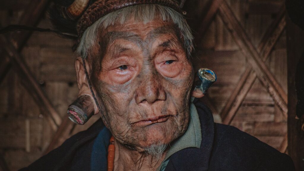 Portrait of tattooed Konyak elder with ear plugs