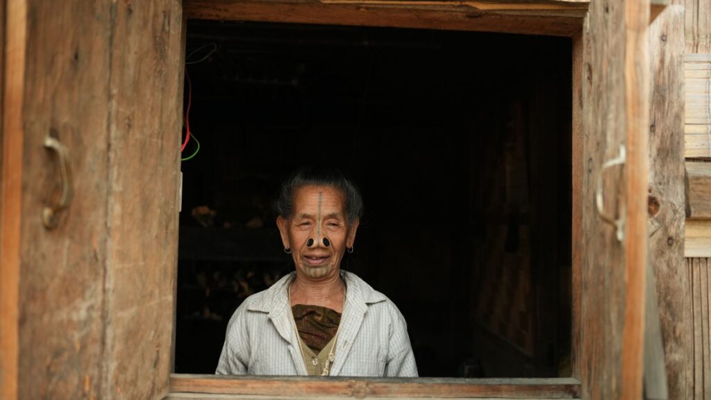 Apatani woman with traditional facial tattoo at doorway