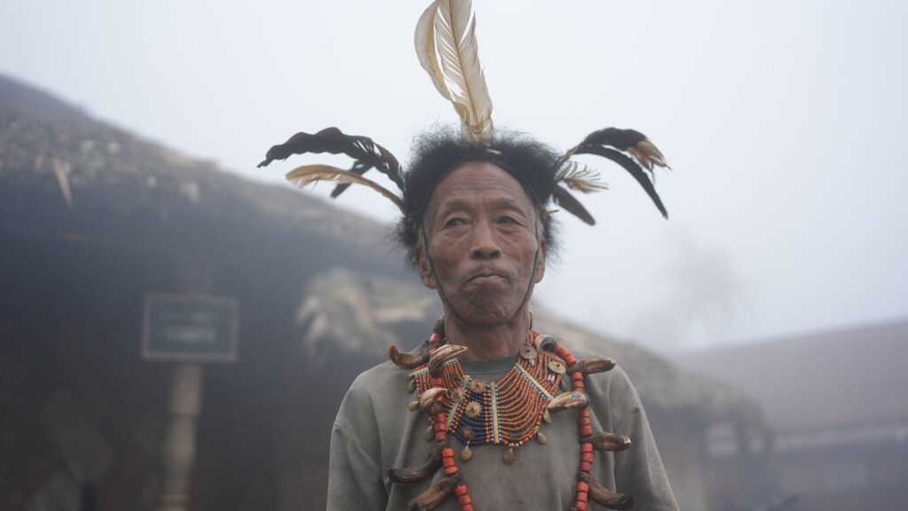 Konyak man wearing feathered headgear and bead necklace