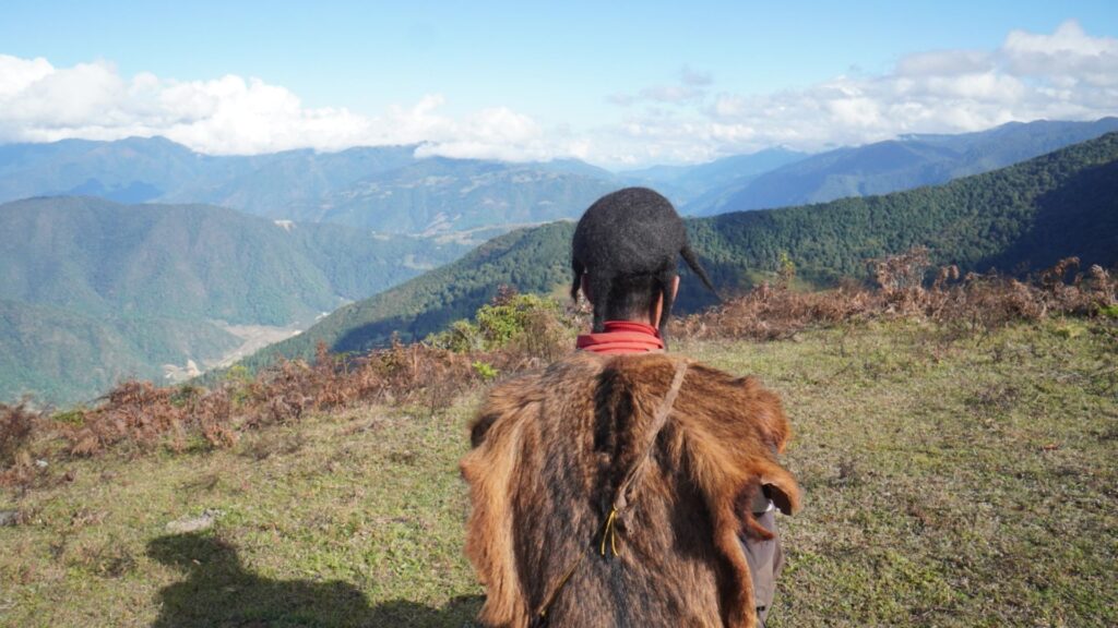 Brokpa herder in yak-hair cloak standing on a high-altitude ridge