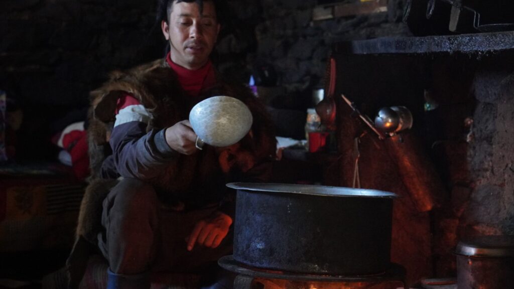 Brokpa man cooking inside a stone house