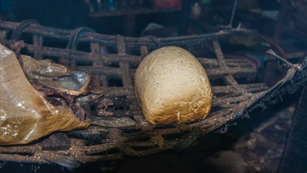 Chhurpi cheese and wrapped food drying on a grill above a hearth.