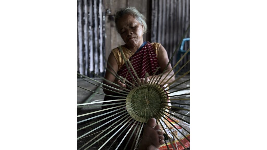 Woman weaving bamboo craft indoors
