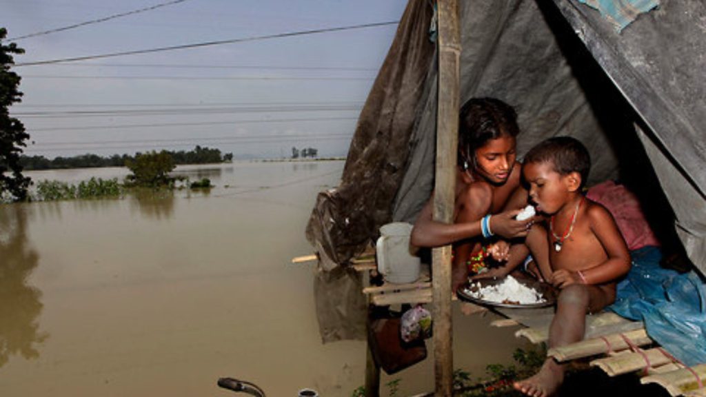 Children eating beside floodwaters